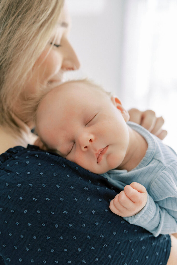 Mother holding newborn baby in natural light.